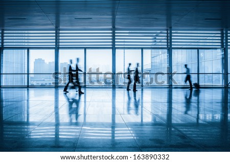 commuters motion blurred with modern corridor in railway station