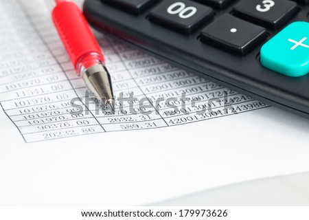 financial documents closeup with calculator and red pen