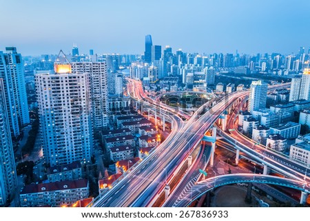 interchange of urban viaducts in nightfall with modern city skyline
