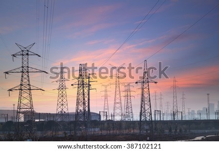 electricity transmission pylon at city suburb against the sunset glow sky