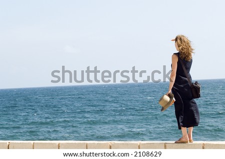 Young woman watching at calm sea from the wall - bright, pastel photo, Mahdia, Tunisia