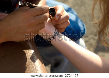 A man making temporary henna tattoo on woman\'s wirst