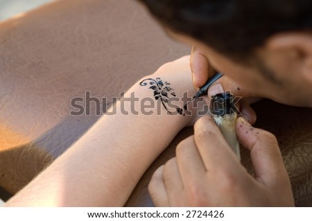 stock photo : A man making temporary henna tattoo on woman's arm