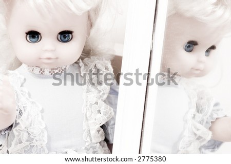 Vintage doll standing at the mirror, blue eyes