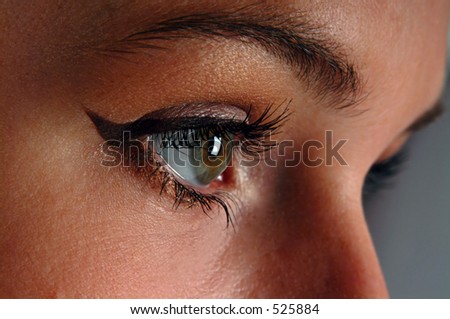 Close up shot of woman\'s right eye showing just applied eyeliner and a little bit of glitter.
