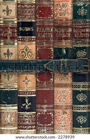Close up of old books bound together by a buckled strap.