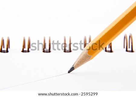 Close up shot of a sharp yellow pencil drawing a straight line on a white paper notebook.
