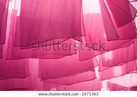 Sheets of cloth dyed pink set out to dry in Marrakesh, Morocco. Back lit by the sun.