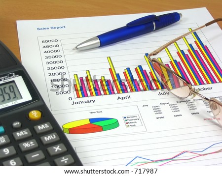 Colorful sales charts, calculator, blue pen and glasses