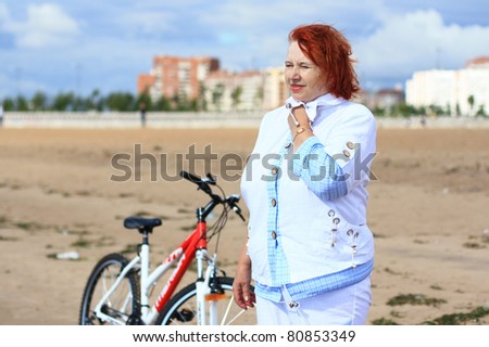An elderly woman stopped to rest after cycling.