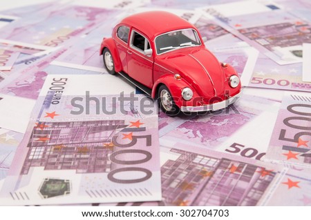 Red model car on banknotes, symbolic photo for car buying,