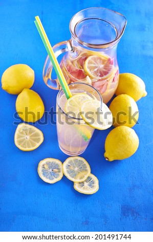 Pitcher of lemonade with lemons, ice and fresh slices on vintage blue wood table - still life