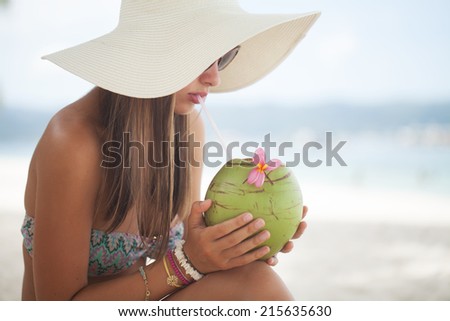 Beautiful woman relaxing on a paradise beach with coconut
