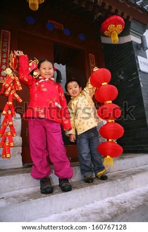 Two children(5-29 years) standing in front of chinese traditional house door smiling