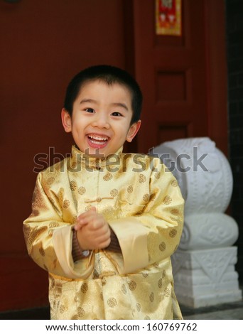 One chinese boy(4-5 years) standing in a Chinese traditional house gate smiling