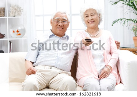 A shot of old couple watching TV at home