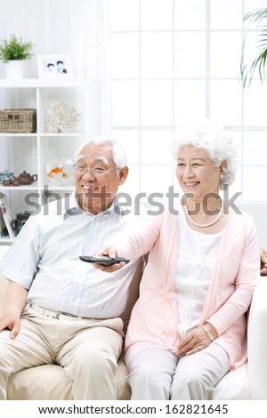 A shot of old couple watching TV at home