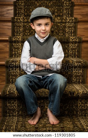 Young brunette caucasian boy sitting on stairs with flat cap