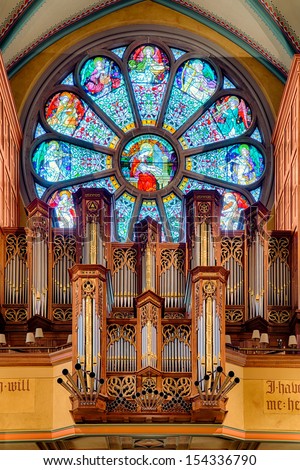 SALT LAKE CITY, UTAH - AUGUST 16: Pipe organ in front of stained glass window at the Cathedral of the Madeleine Roman Catholic Church on August 16, 2013 in Salt Lake City, Utah