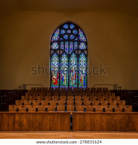 HOLLAND, MICHIGAN - MAY 13: Stained glass window above wooden chairs in the Dimnent Memorial Chapel on the campus of Hope College on May 13, 2015 in Holland, Michigan