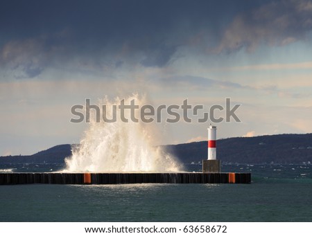 Lake Michigan waves splash over a breakwall by lighthouse in Petoskey, Michigan
