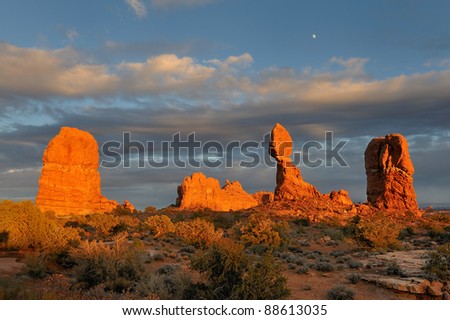 Sunset with Balanced Rock and other rock formations under the Moon in Arches National Park near Moab, Utah