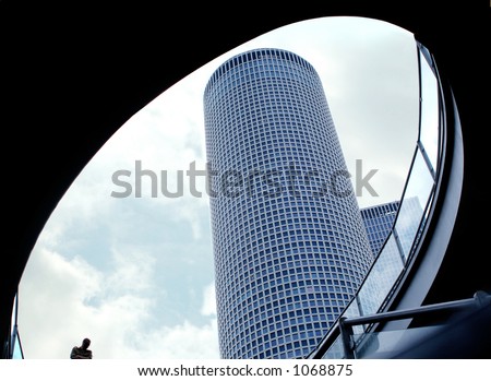 modern building shot from under the bridge with an oval opening and a person descending the stairs