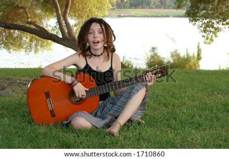 young beautiful woman,playing the guitar and singing in the park