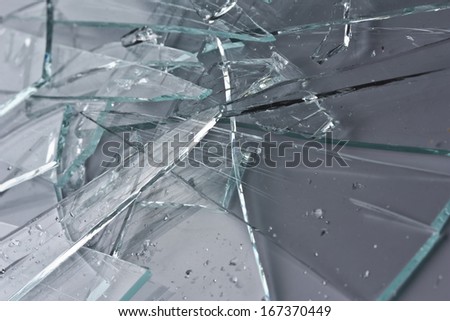 Broken glass fragments above grey. Abstract background texture