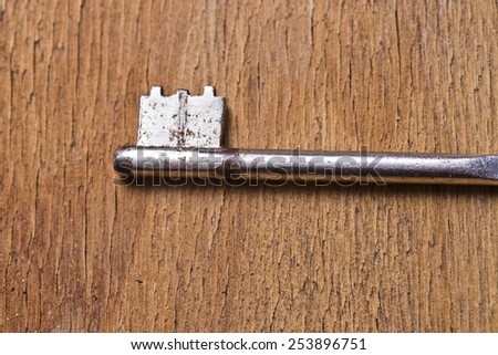toothed portion of single key on a old wooden table
