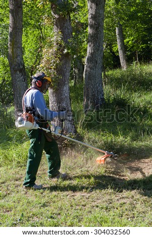 Gardener cutting grass with string trimmer