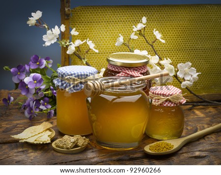still life of jars of honey and pollen with a spoon.
