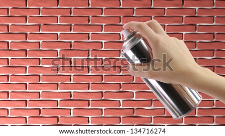 Human hand holding a graffiti Spray can in front of a brick wall