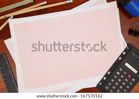 Cross-section paper with pencils on wooden background