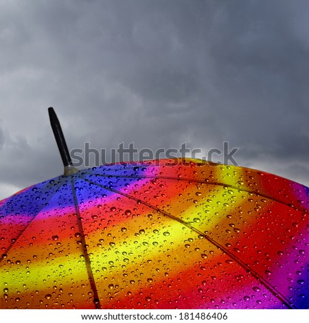 Colorful umbrella top with raindrops and heavy clouds