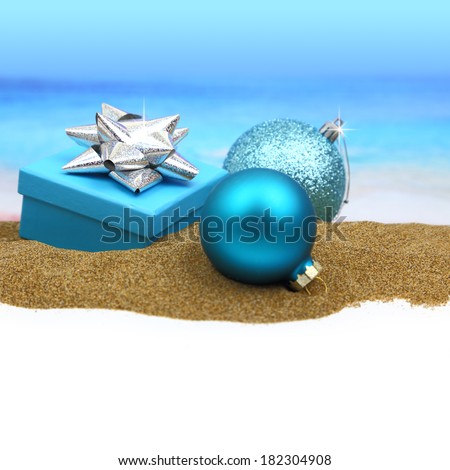 Gift box and Christmas balls on the sand