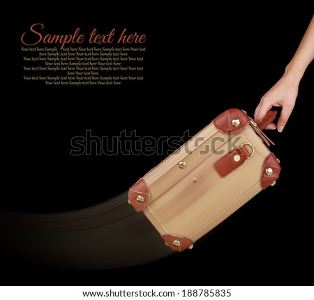 Hand dragging a travel suitcase isolated on black