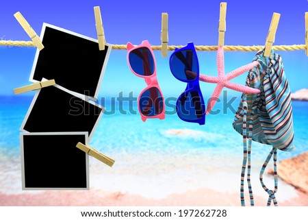 Photo frames and beach items hanging on a rope in front of the sea