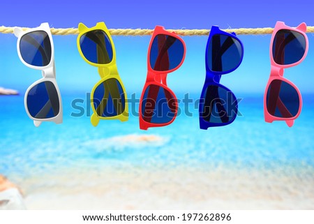 Colorful Sunglasses hanging on a rope in front of the sea