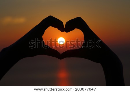 Golden sunset with hands silhouette in shape of heart