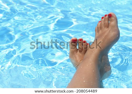 Female wet feet in the clear water of the pool