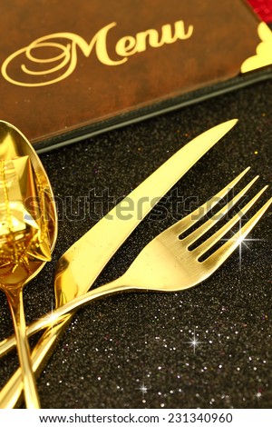 Christmas golden cutlery and restaurant menu on festive background