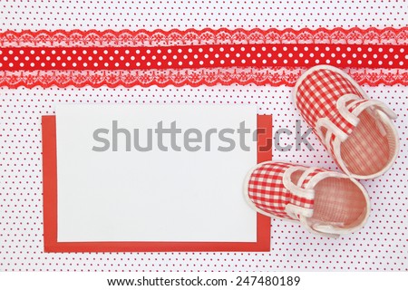 Baby shoes and blank card on polka dots background