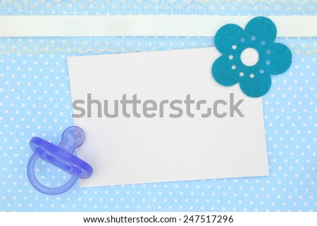 Blank card and blue pacifier on decorative polka dots background