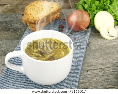 Fresh onion soup in a soup cup, over an old wooden background