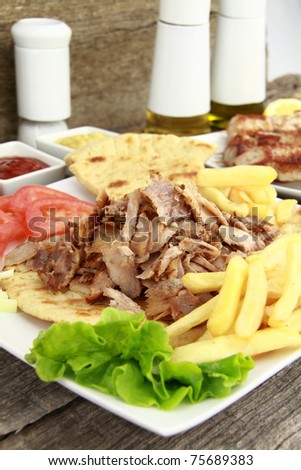 Plate of traditional Greek gyros or Turkish kebab with meat, fried potatoes, tomato and onion