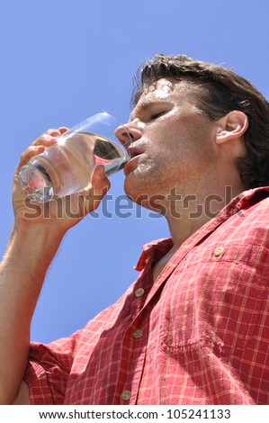 Inferior shot of hot sweaty thirsty man drinking a glass of water