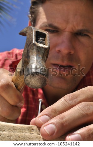 Inferior shot of man concentrating as he hammers a nail in wood