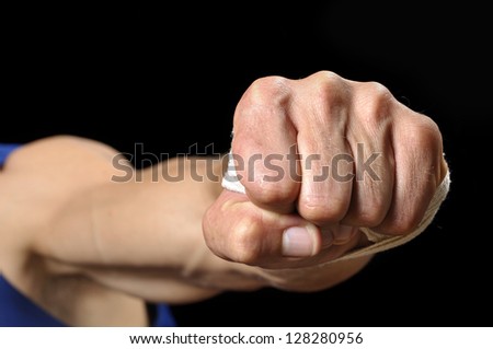 Closeup of muscular man throwing fist at camera on black background