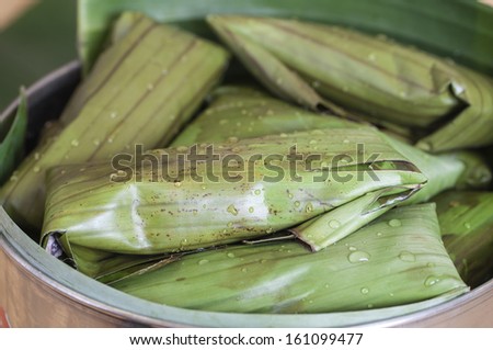 Macro closeup of full pot of tamales wrapped in banana leaves and ready to cook